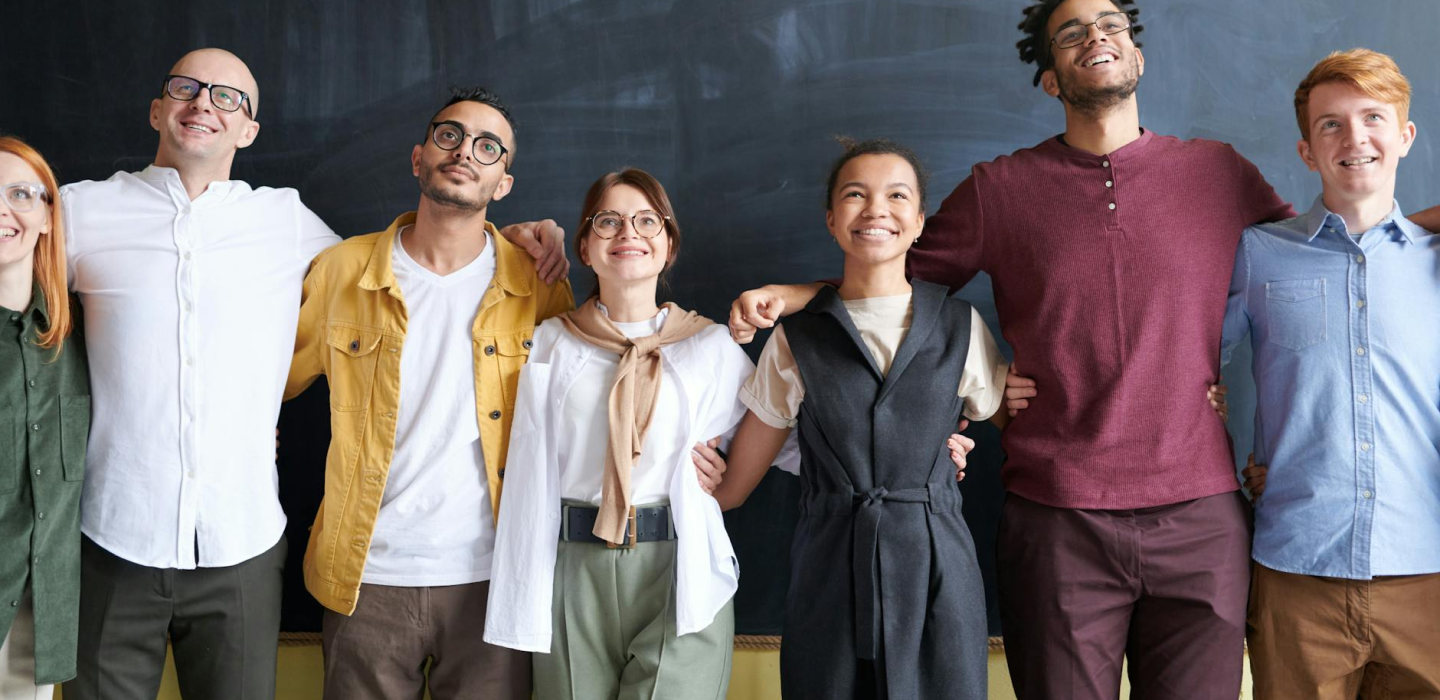 image of 7 people smiling with arms over each others shoulders