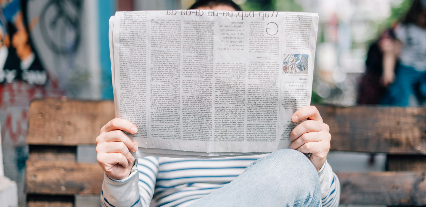 person sitting on a bench reading a newspaper