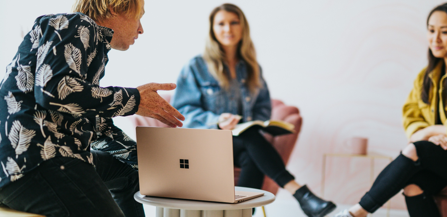 3 team members sat round a laptop having a discussion